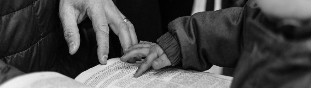 Adult hand and child hand touching a book.